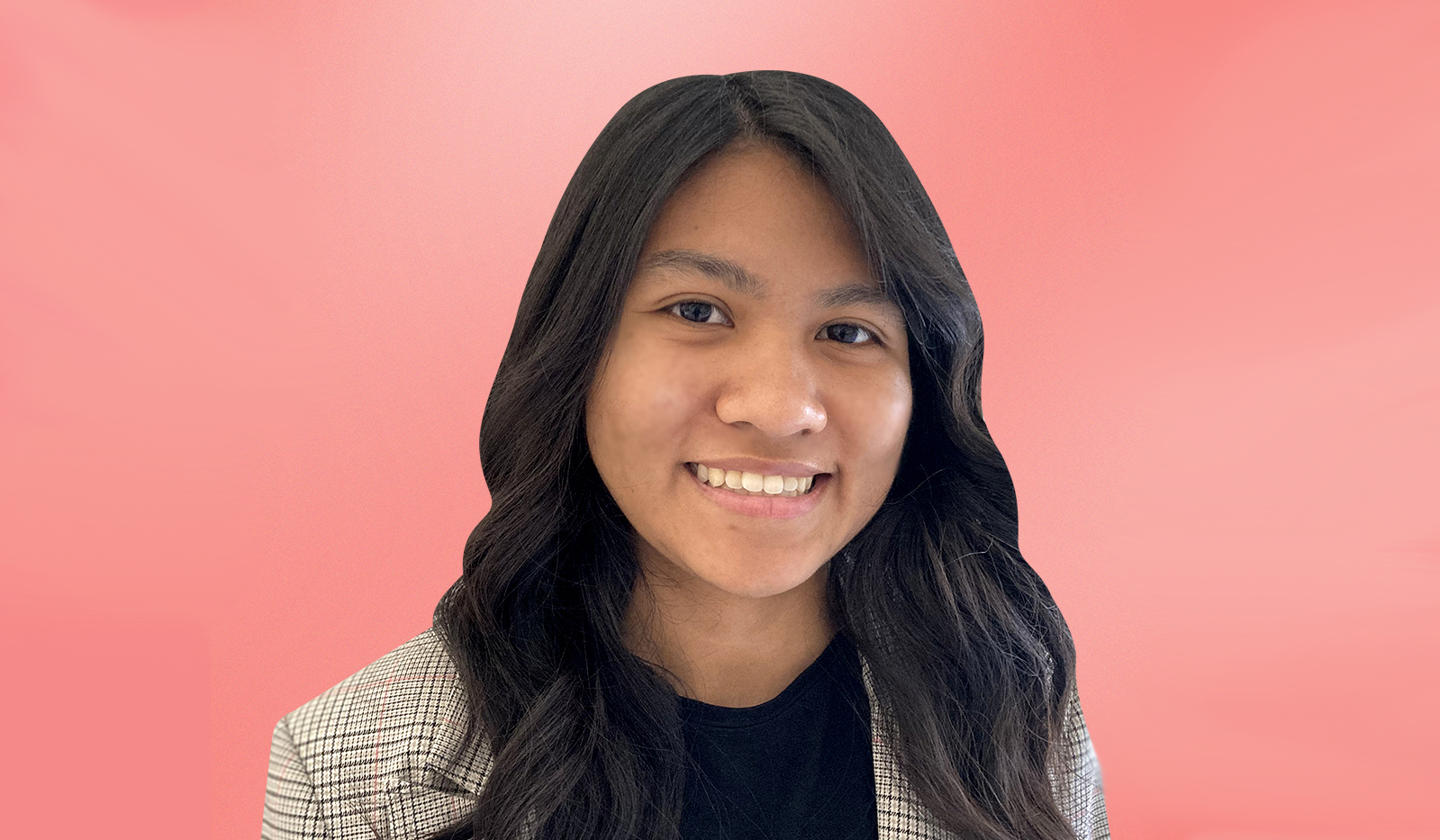 A woman with dark hair smiles in front of a pink background.