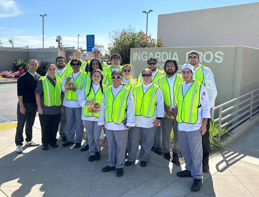 Students bright safety vests pose in front of Ingardia Bros. produce warehouse.