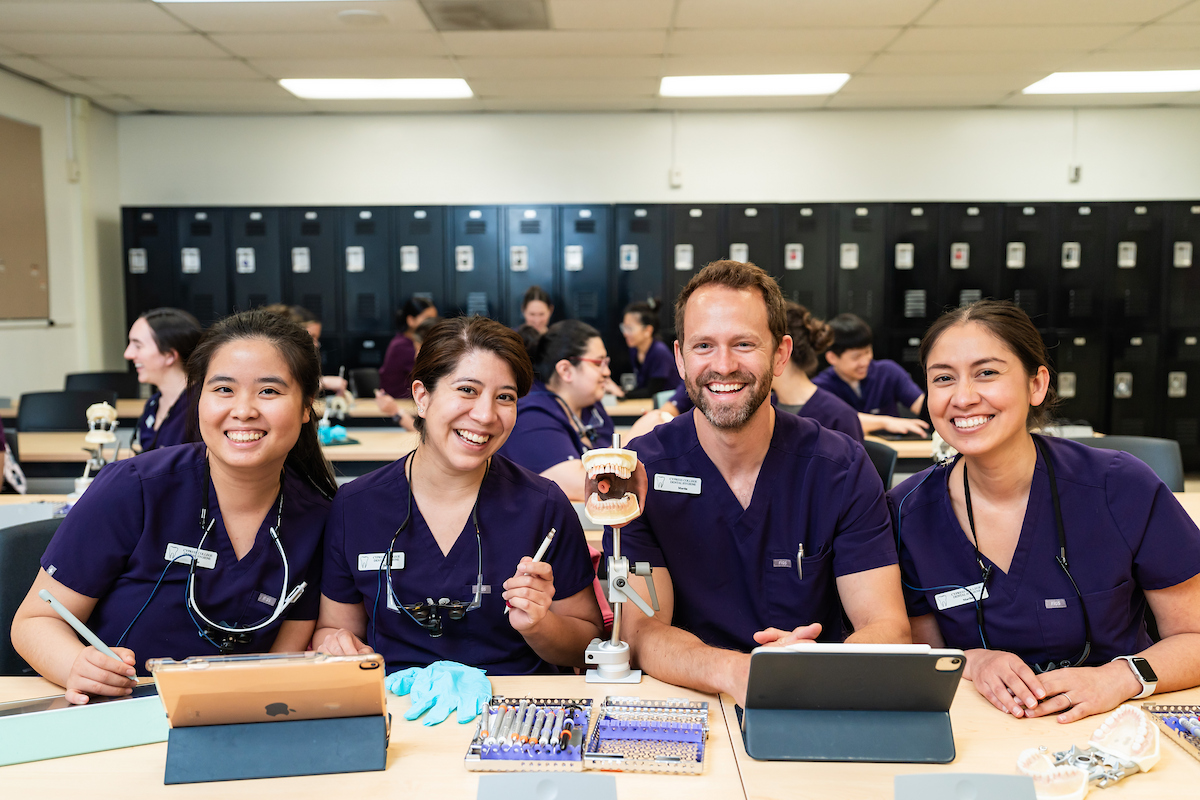Dental Hygiene students wear scrubs and smile for the camera